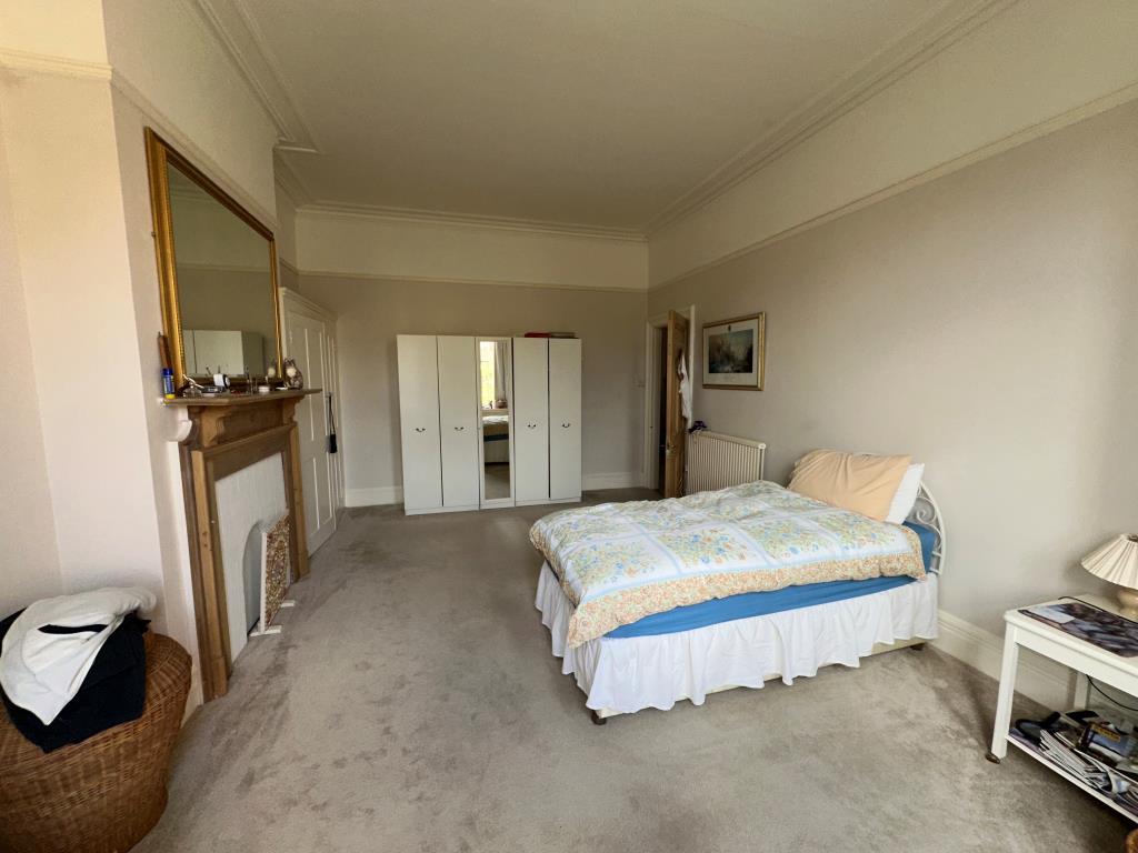 Lot: 74 - SUBSTANTIAL THREE-BEDROOM GARDEN FLAT FOR REFURBISHMENT - Main bedroom with built in storage and fireplace